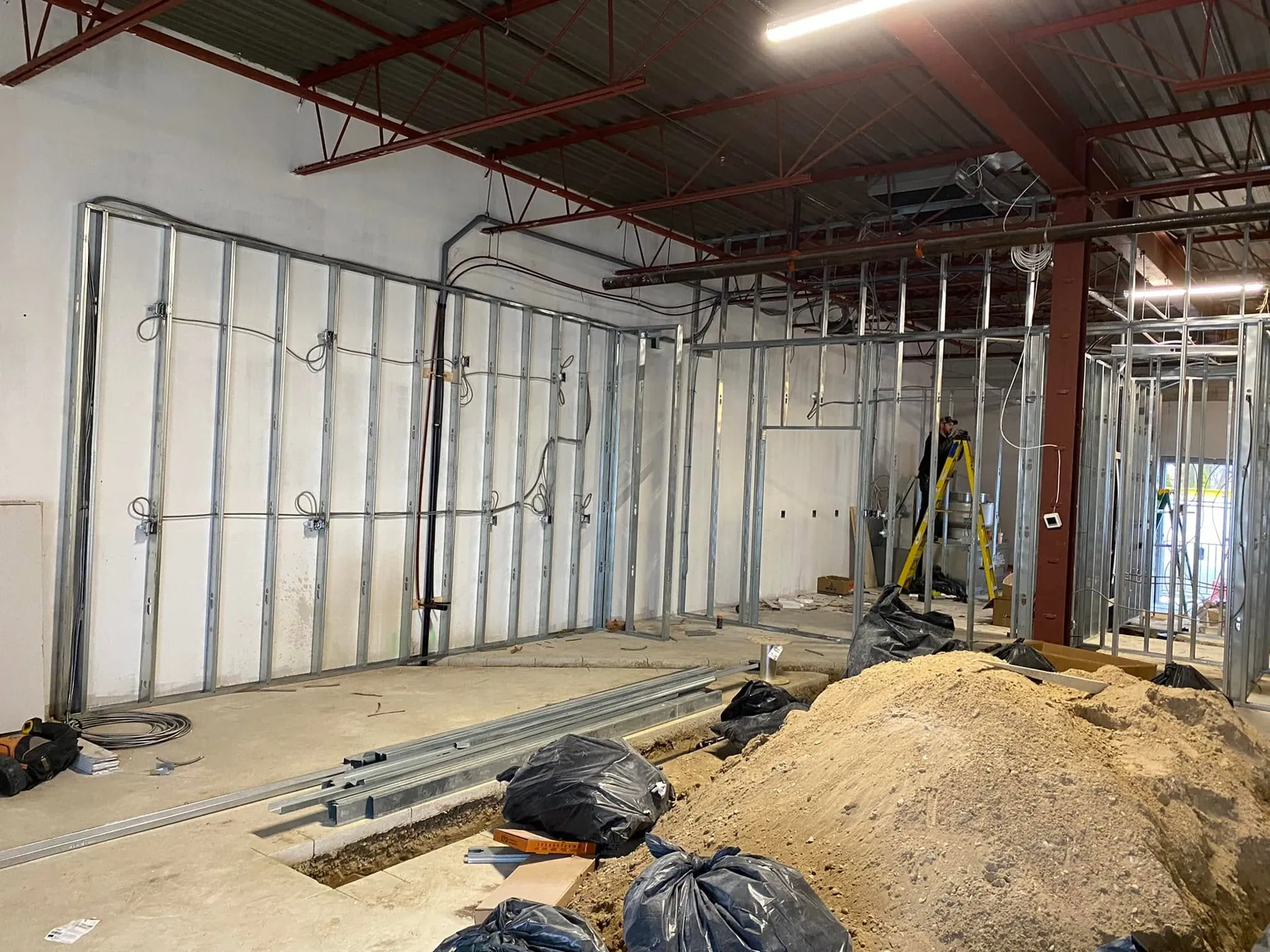 Electrical boxes and wiring installed through metal studs in a retail fit-out.