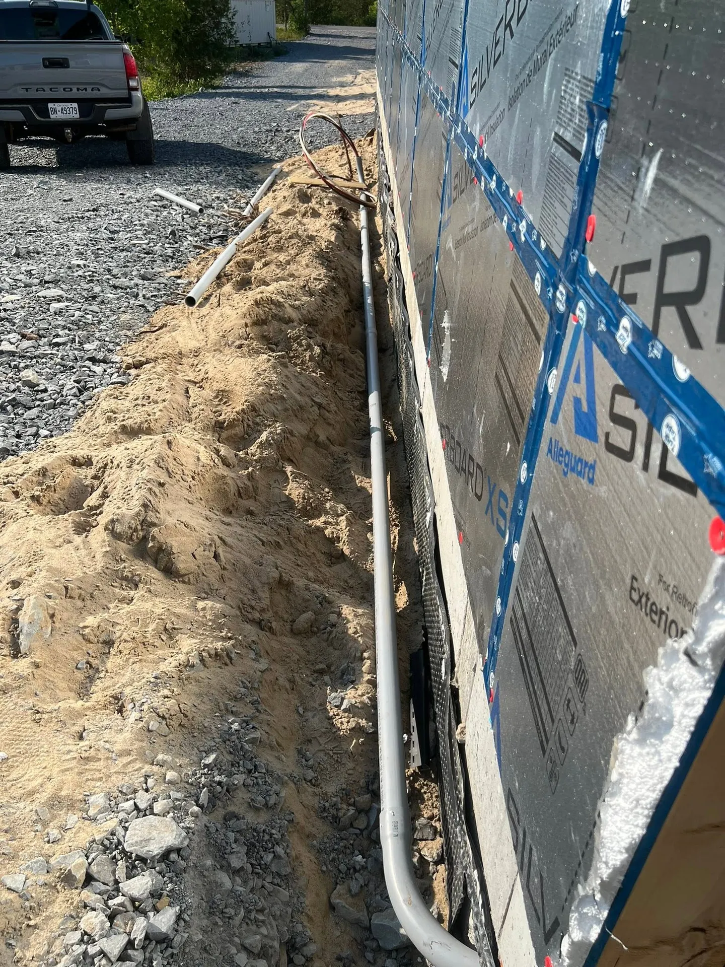 PVC electrical conduit installed in a trench beside a new building.