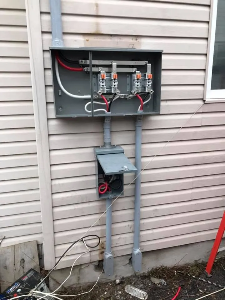 Open meter base and service conduit during an electrical upgrade on a vinyl-sided home.
